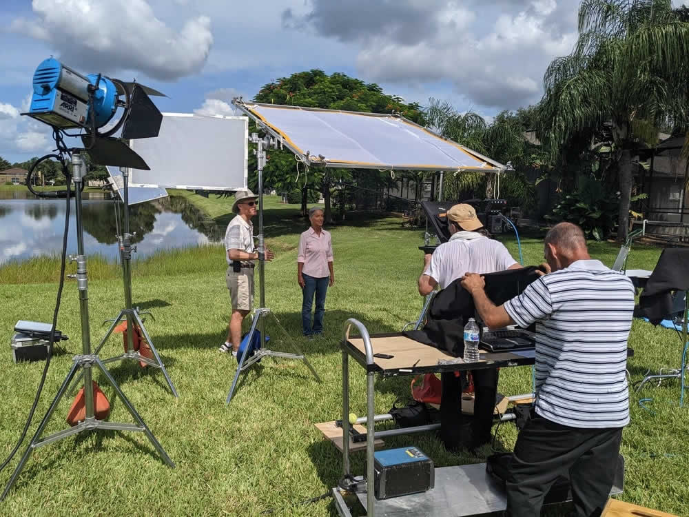 people on a lakeshore shooting a commercial, surrounded by camera and lighting equipment