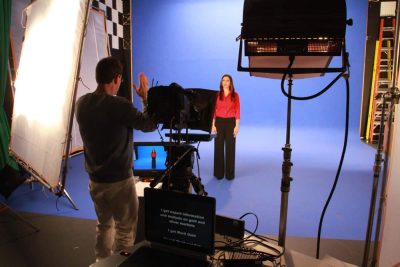 actor/woman standing on a stage in front of a blue screen
