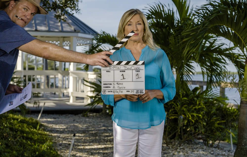 woman standing on exterior film set with camera slate in front of her